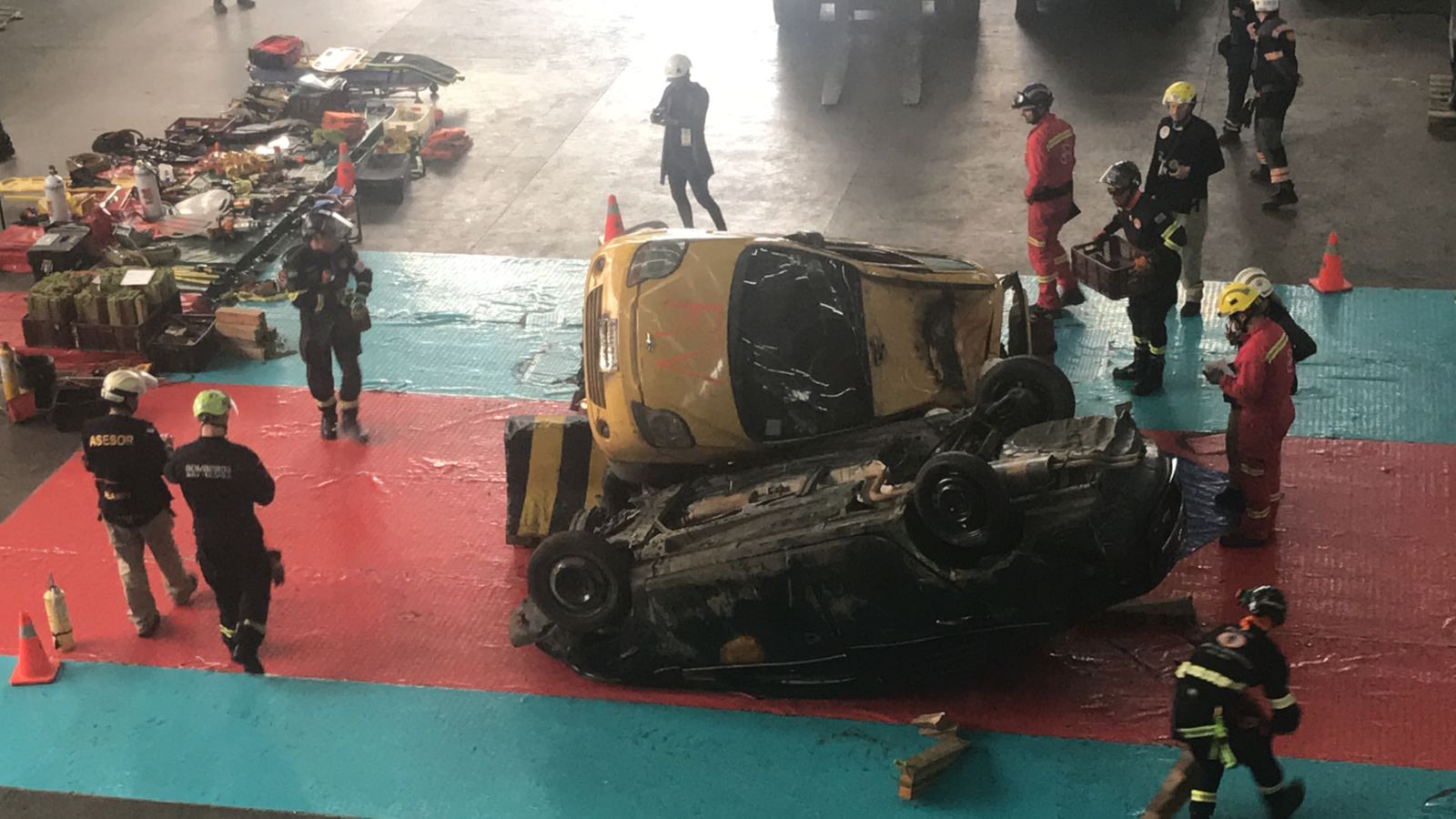 Vista elevada de equipos de rescate trabajando sobre vehículos apilados en un recinto de entrenamiento